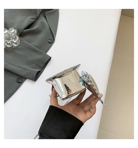 Silver graduation cap shaped shoulder bag with reflective mirror finish held by hand