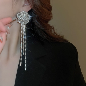 Close-up of silver tassel earrings with diamond flowers worn on a model's ear