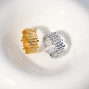 Close-up of gold and silver stainless steel rings with unique wavy textured geometry