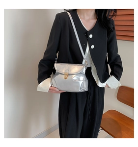 Detail of silver metallic cloud bag with golden circular lock worn by a model