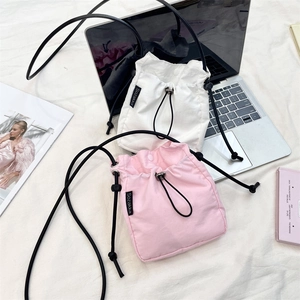 Dettaglio delle borse a secchiello in nylon rosa e bianco con coulisse su sfondo in tessuto