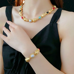 Vintage gold jewelry set with triangle beads and colorful stones on a black background