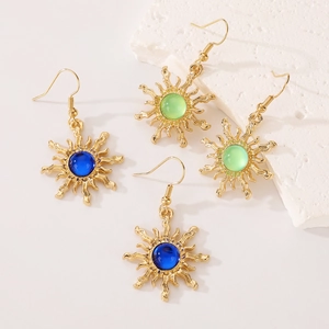 Detail of sunburst pendant earrings with blue and green gemstones on white stone base