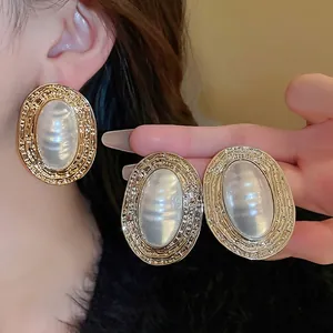 Vintage oval earrings with hammer-textured gold finish and iridescent faux pearl