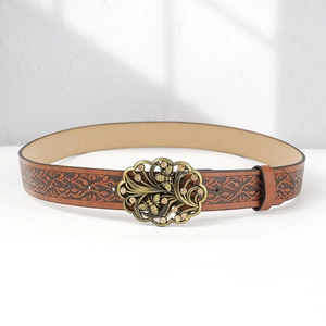 Detail of bohemian brown leather belt with embossed floral patterns and bee buckle