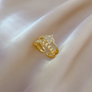 Detailed view of gold star ring with micro-pave zircons and double layer chain on beige satin
