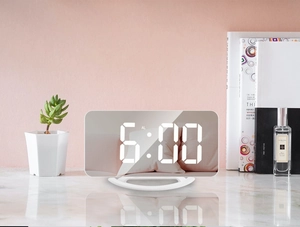 Close-up of white mirror digital alarm clock on marble desk showing 6:00 time display
