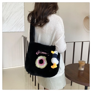 Detail of black plush crossbody bag with sweet donut embroidery and a duck charm accessory