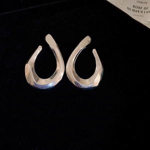 Close-up of silver geometric twisted hoop earrings on high-quality black velvet background