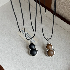 Minimalist resin gourd pendant necklace with black cord and vintage metal frame design