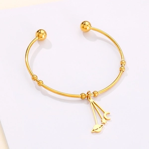 Detail of gold moon and star celestial charms on adjustable stainless steel open bangle