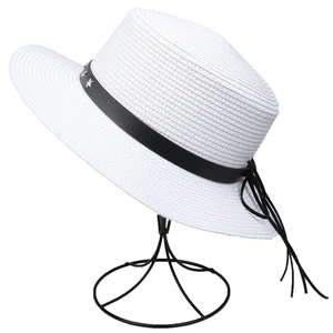 Detail of white straw sun hat featuring a black leather band with silver star buckles
