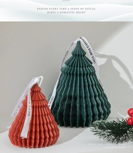 Close-up of origami Christmas tree candles with ribbons and festive pine branch decor