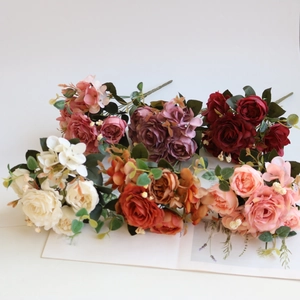 Detailed close-up of artificial silk rose bouquets in multiple colors on a white surface