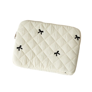 Quilted cream laptop sleeve with black bow embroidery and secure silver zipper closure