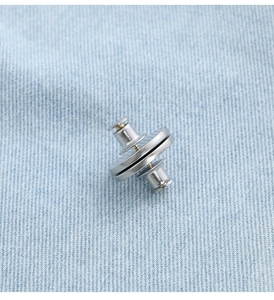 Detailed view of silver magnetic curtain buckles with pins on blue fabric texture