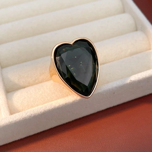 Detail view of heart-shaped dark green gemstone set in a minimalist gold ring mount