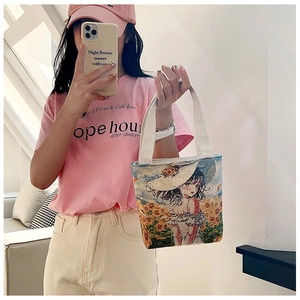 Detailed close-up of a canvas tote bag featuring an embroidered girl in a sunflower field