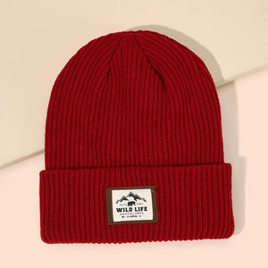 Close-up of dark red ribbed knit beanie with Mountain Bear Wild Life woven label detail