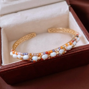 Macro view of 18K gold-plated bangle with pearls and amethyst in a leather box