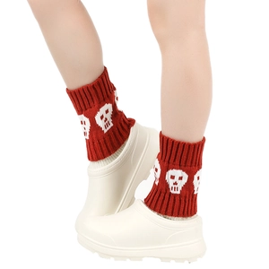 Detail of red knitted boot cuffs featuring white skull patterns and ribbed texture for winter