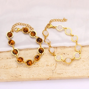 Detail of gold beaded bracelets with tiger eye and white stones on silk background
