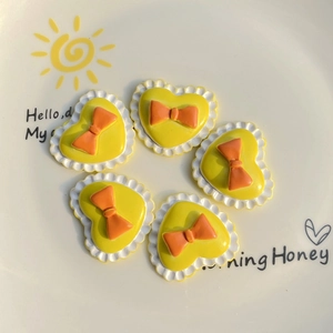 Detailed view of yellow heart-shaped resin charms with orange bows for DIY crafts