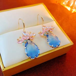 Detailed macro view of butterfly drop earrings with blue and pink zircons in a gift box