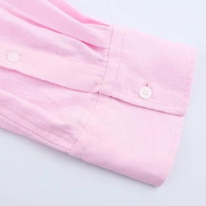 Detailed close-up of pink long sleeve shirt cuff with two white resin buttons