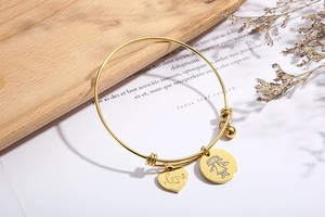 Detail of adjustable golden stainless steel bangle with Love heart and girl charms