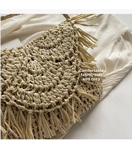 Close-up of hand-woven straw bag featuring fine crochet texture and long fringe tassels
