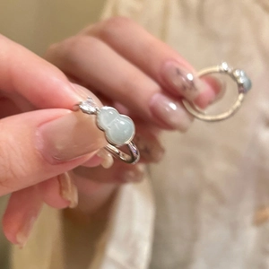 Detail of a silver gourd ring with light green stone and zircon on a hand