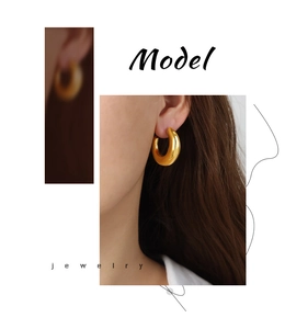 Close-up of chunky gold-plated C-shaped earrings with a minimalist metallic texture