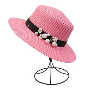 Detail of pink woven sun hat featuring black ribbon with pearl and floral ornaments