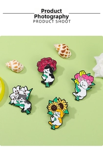 Detailed set of four enamel cat brooches holding colorful flowers on a soft green background