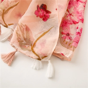 Detailed view of pink floral print scarf fabric with soft woven fringe edge and thin texture