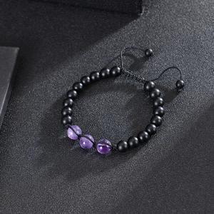 Adjustable 8mm matte black stone beaded bracelet with three purple amethyst beads on dark background