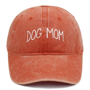 Macro detail of DOG MOM white embroidery on washed rust-red cotton baseball cap texture
