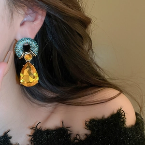 Close-up of vintage court style drop earring featuring yellow teardrop crystal and blue accents