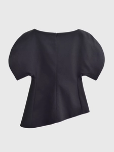 Détail d'un haut noir à manches bouffantes avec ourlet asymétrique et zip discret