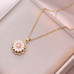 Gold daisy pendant necklace with pink enamel and pearl on a premium jewelry stand