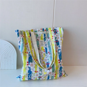 Détail du sac fourre-tout en toile à rayures et fleurs sur un support minimaliste