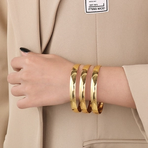 Close-up of three polished 8mm gold stainless steel bangles on a female wrist