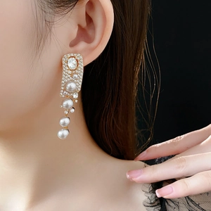 Detailed close-up of a model wearing long tassel earrings with white pearls and crystals