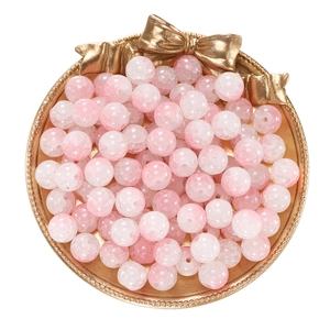 Macro shot of 10mm pink ice-crack glass beads for DIY jewelry in a gold bow tray