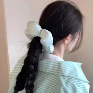 Detail of mint green floral hair scrunchie shown on a braided hairstyle in soft indoor light