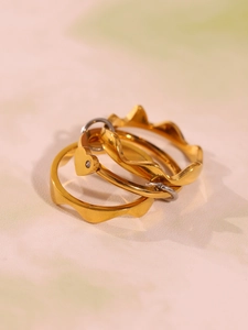 Détail d'un ensemble de trois bagues dorées avec zircon en cœur et anneaux ondulés minimalistes
