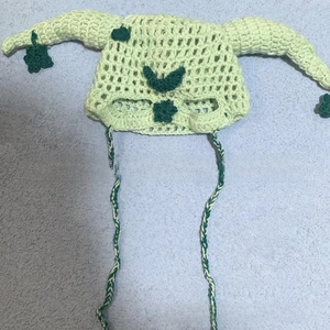 Detail of light green hand-crocheted knit hat with devil horns and clover pattern