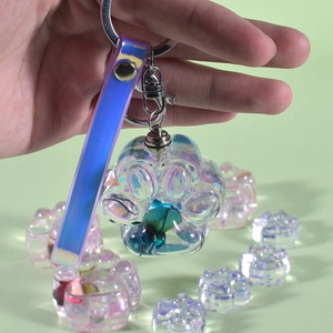Close-up of resin cat paw keychain with blue dried flower and iridescent wrist strap