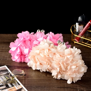 Detailed view of pink and beige fabric floral petal evening clutch bags on a dark surface